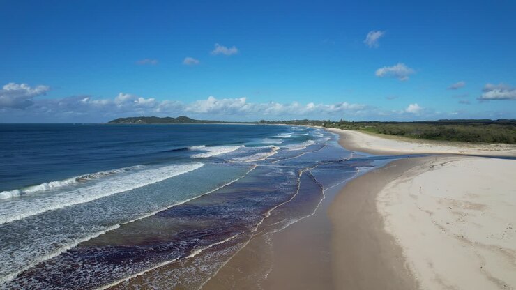 Belongil Beach mit Meereswellen, die an den Sandstrand in New South Wales, Australien, schlagen – Drohnenaufnahme