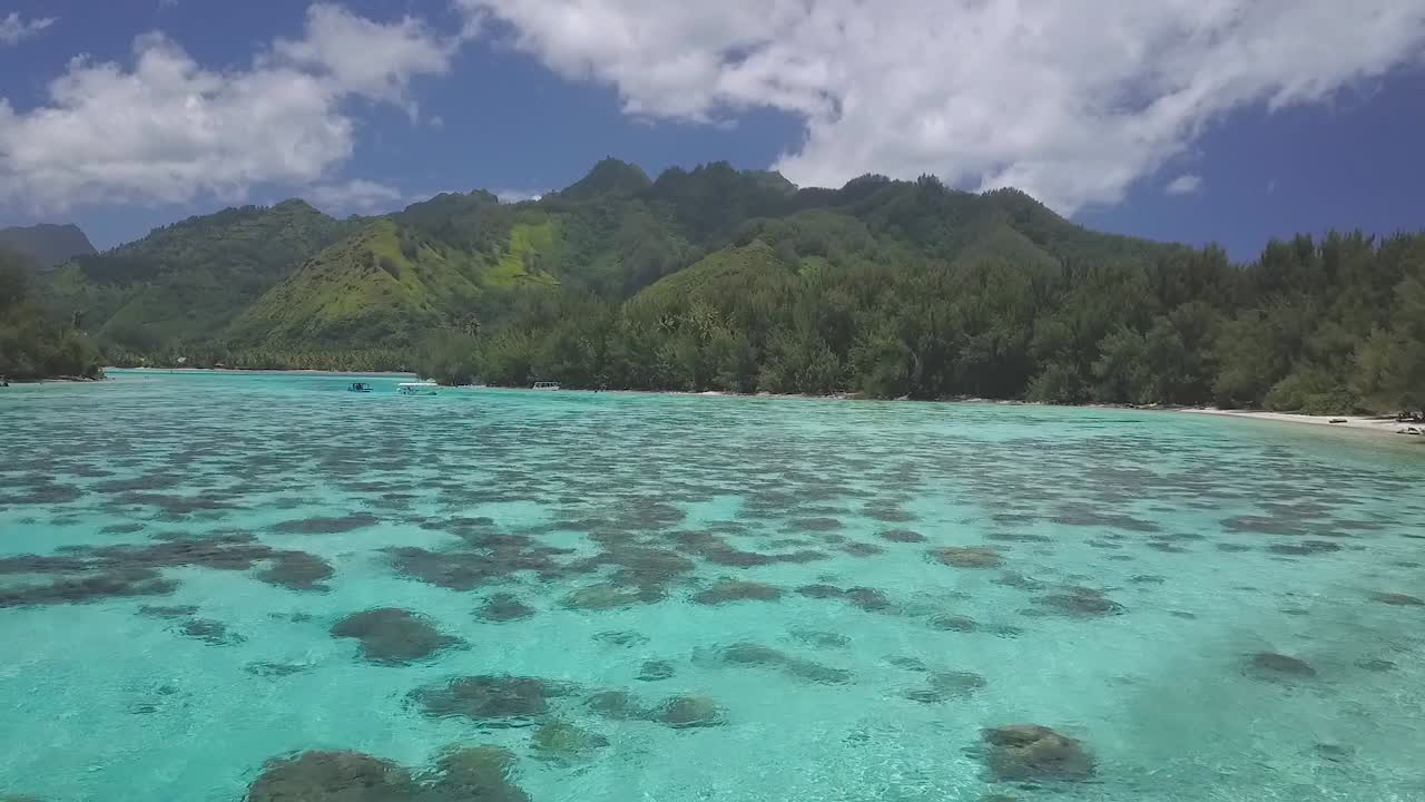 drone flying over shallow bay with clear tropical water in French Polynesia