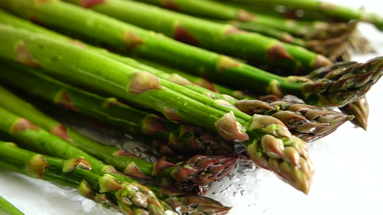 Fresh green asparagus. Water splashes. Slow motion.