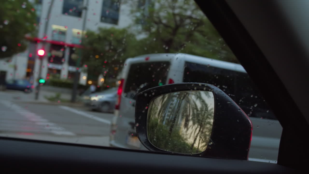 viaje en un día de lluvia: el paisaje de la ciudad reflejado en el espejo lateral del coche