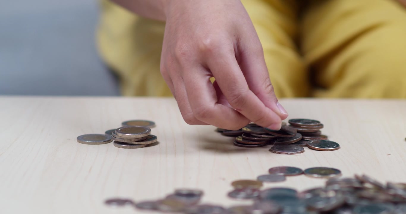 Uma pessoa organiza moedas numa mesa, enfatizando a importância de poupar dinheiro de forma eficaz.
