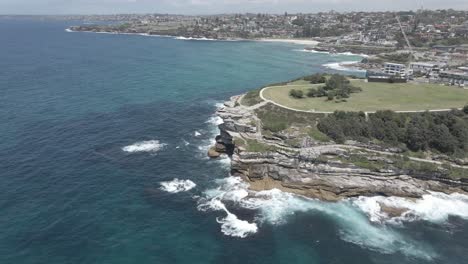 Luftaufnahme-Der-Halbinsel-Mackenzies-Point-Mit-Meereswellen,-Die-Auf-Einer-Felsigen-Bucht-Zusammenbrechen---Tamarama-Beach,-NSW,-Australien