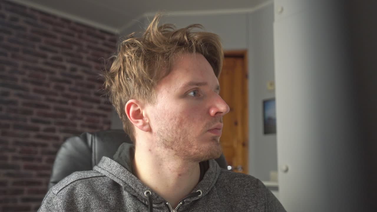 흐트러진 머리를 한 청년이 컴퓨터 모니터를 읽고 있다