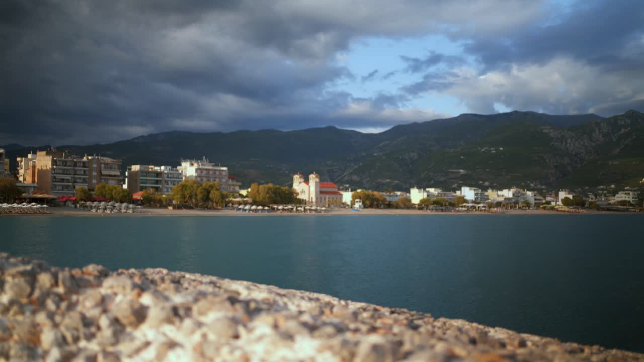 View of Kalamata city from dark pier , revealing behind a cement block breakwater , pedestal shot 4K