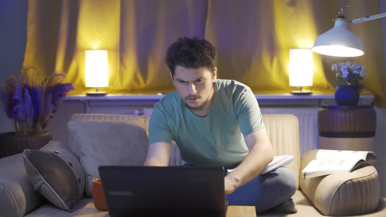 Male student studying at night in laptop light.