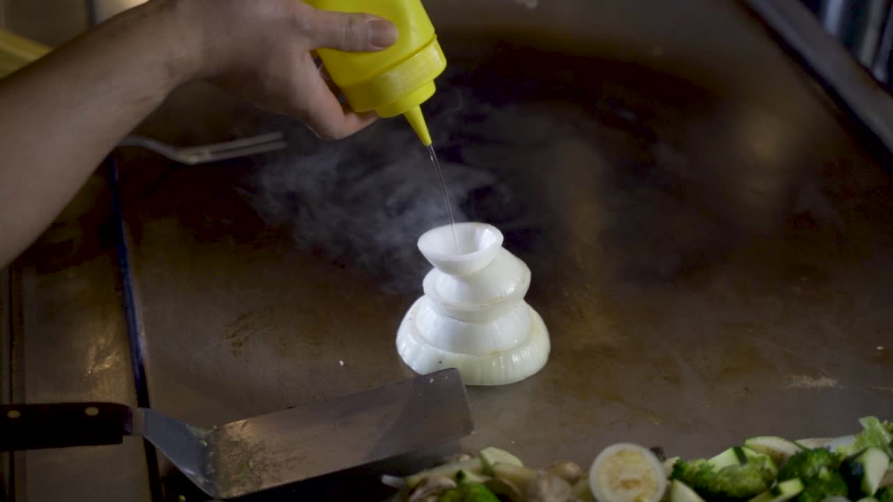 Traditional onion volcano in teppanyaki dining gets filled with oil, slowmo HD