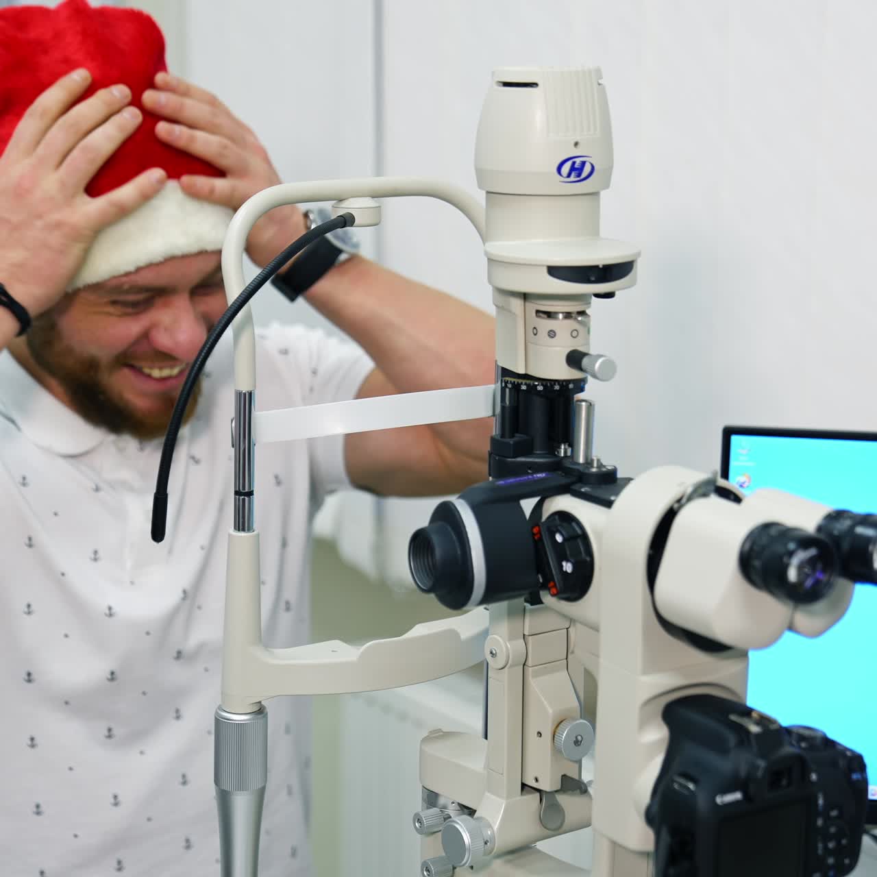 Doctor examining eye with medical equipment. Ophthalmologist check eyesight of young man in christmas cap