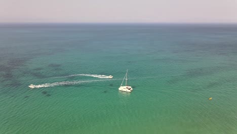 toma aérea alrededor del catamarán en el mar turquesa con otros barcos pasando