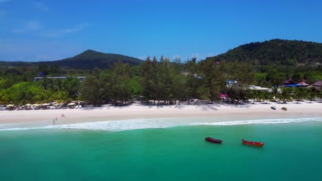 tropical hut on white sand beach meeting calm turquoise water in koh rong island, cambodia. beautiful aerial view flight pull in drone