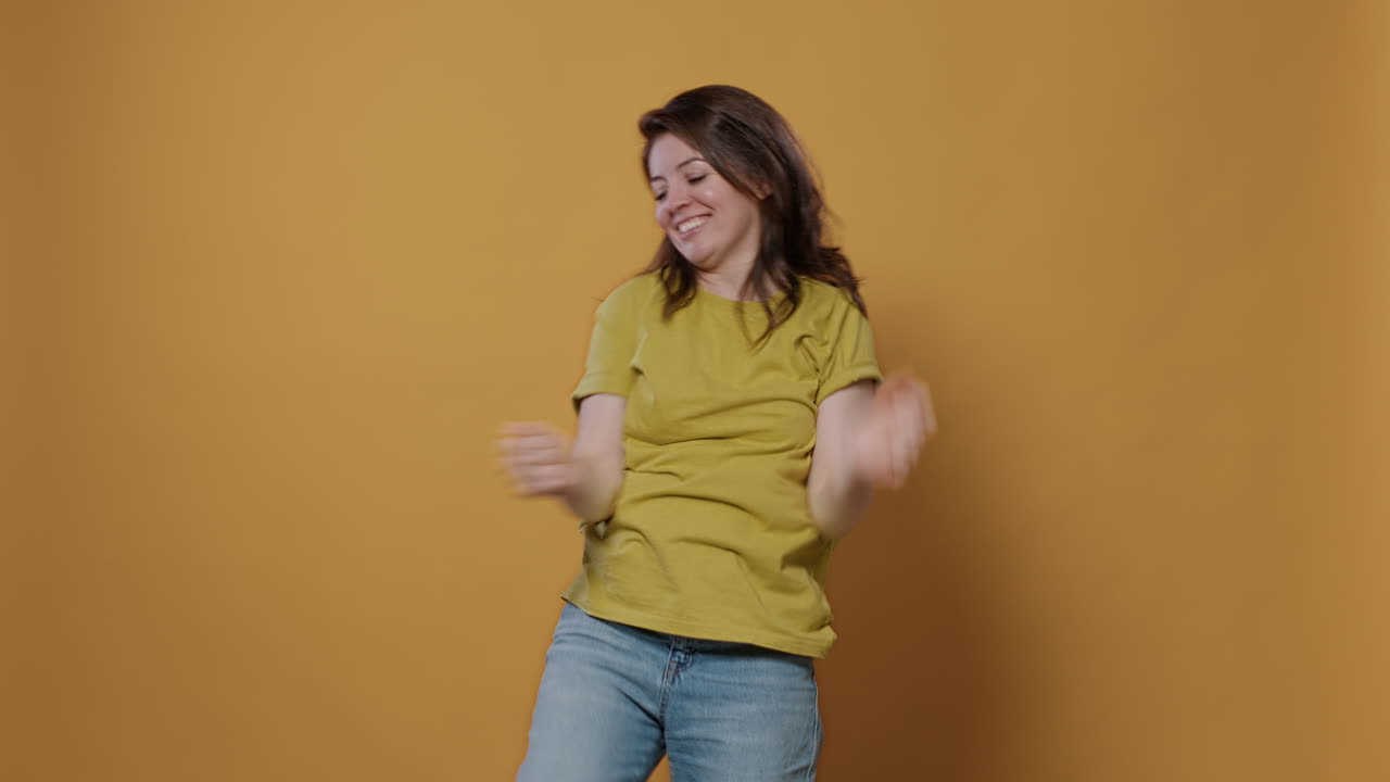 Woman dancing happily on yellow background