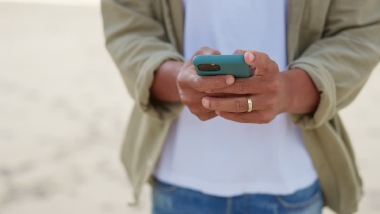 manos escribiendo en el teléfono, hombre en la playa