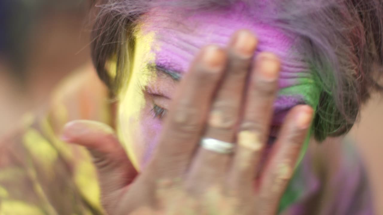 Indian man close-up of face smeared with bright Holi colors