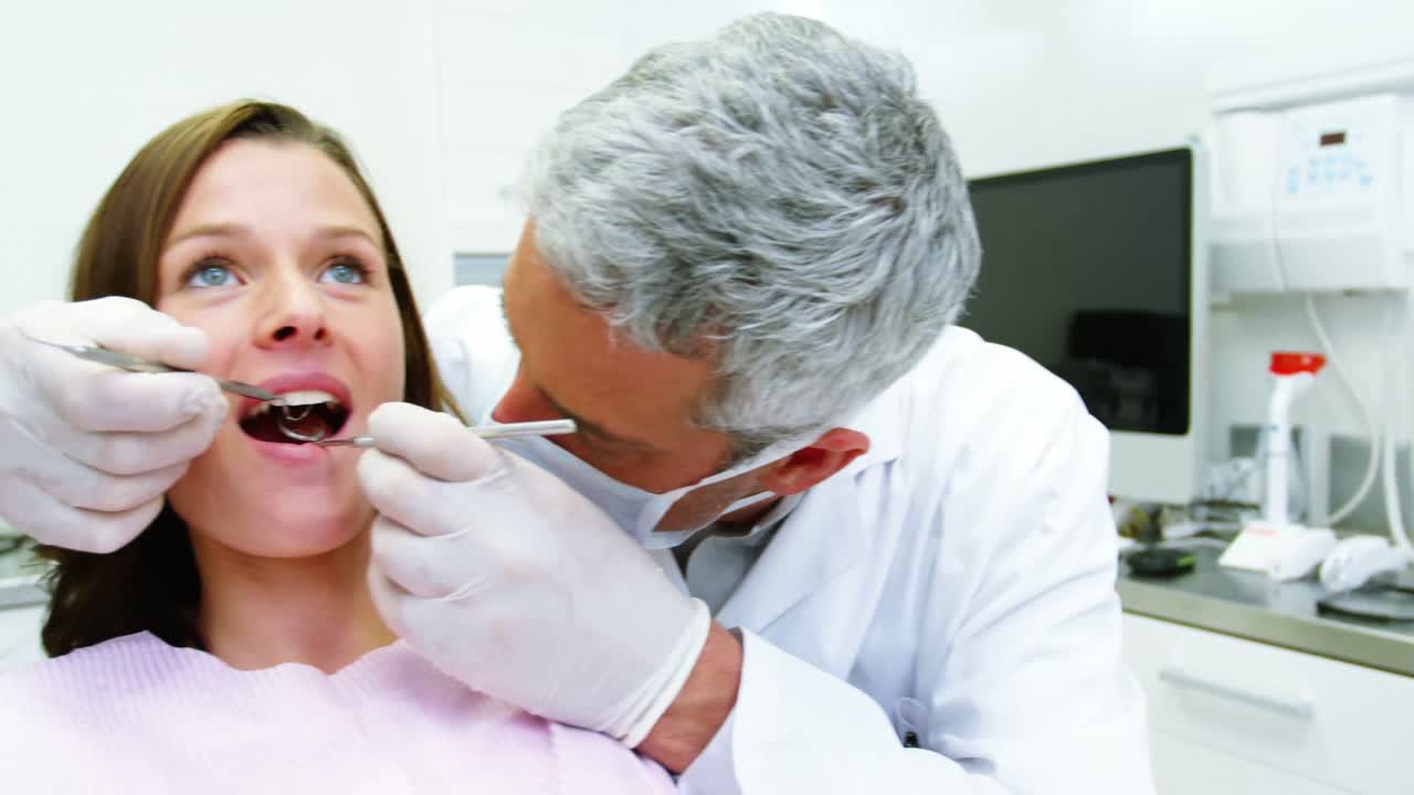 dentista examinando a una paciente con herramientas dentales