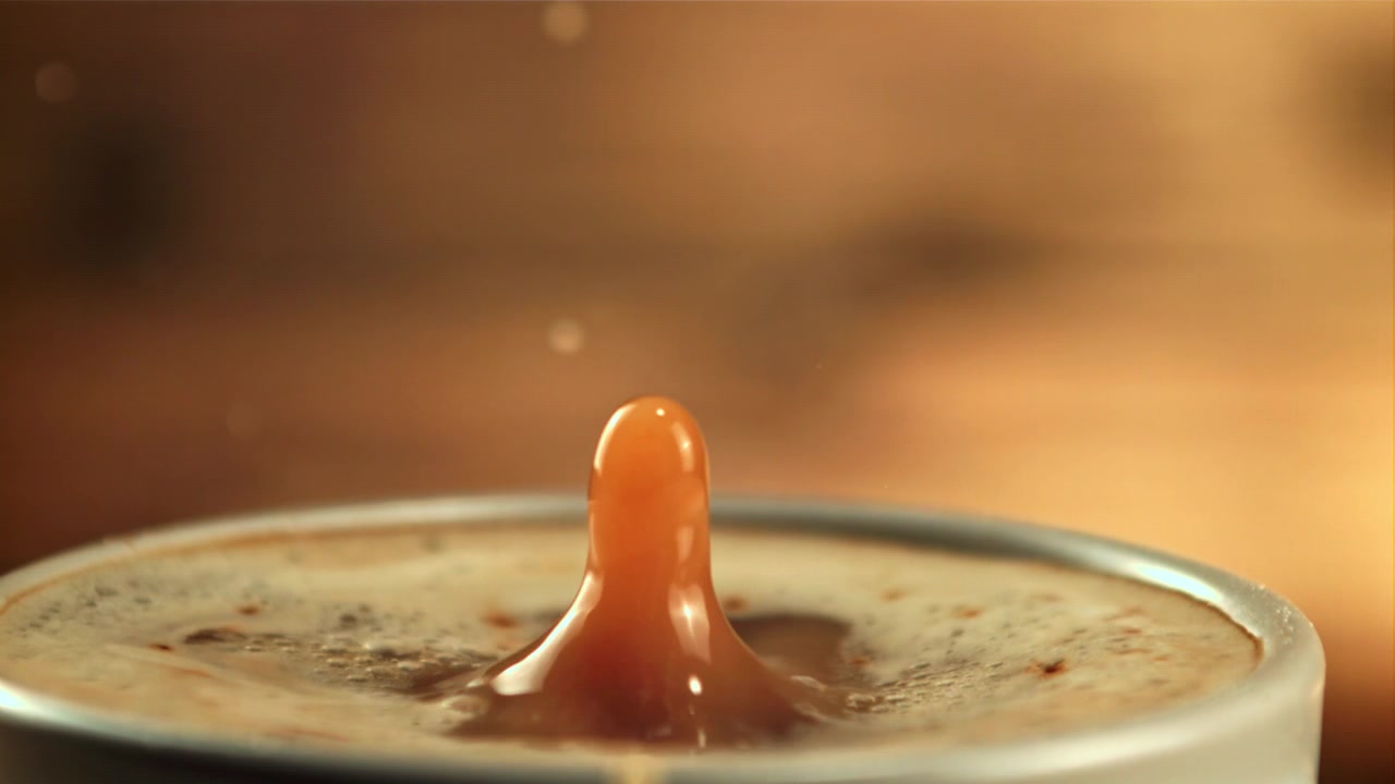 Goccia di caffè che schizza al rallentatore in una tazza con schiuma