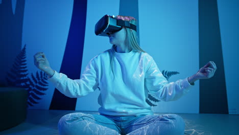 chica con un auricular de realidad virtual sentada en una postura de meditación, vista delantera