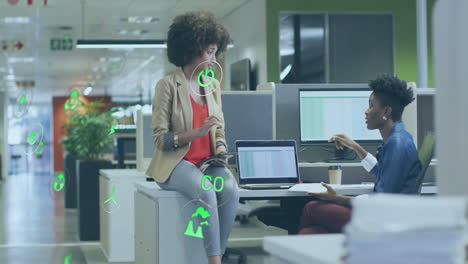 Animation-of-icon-in-circles-over-diverse-female-coworkers-discussing-and-giving-high-five-on-desk