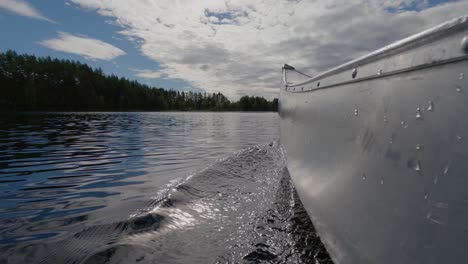 CU-view-of-canoe-traveling-in-water-on-Swedish-lake-kayak-boat-on-a-large-lake-with-blue-clouded-sky