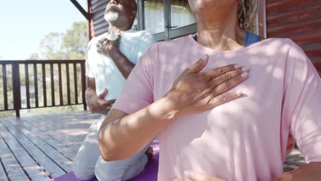 Focused-senior-african-american-couple-practicing-yoga-on-mats-on-sunny-terrace,-slow-motion