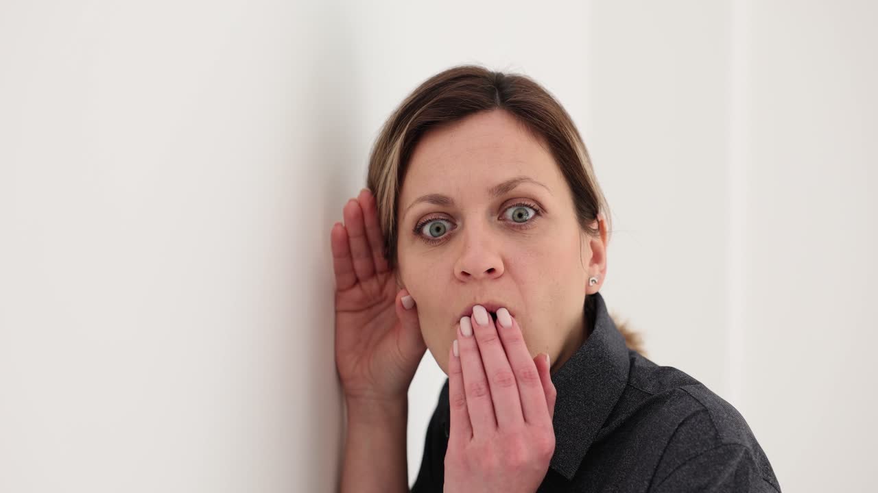 Woman eavesdropping against a wall