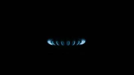 burning gas stove hob, blue flames macro close-up in the dark on a black background. gas is switching on, apearing blue flame. gas stove on isolated on a black background.