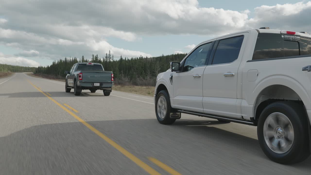 Back view of 2 trucks on the road following each other