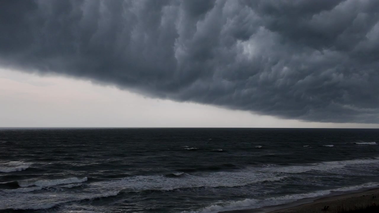 Nuvole temporalesche dense si estendono sul mare, creando uno sfondo oceanico cinematografico pieno di tensione, movimento e drammaticità naturale.