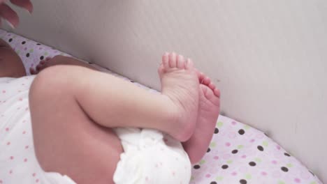 bebé recién nacido en la cuna de cerca los detalles y la mano de la madre tocándola