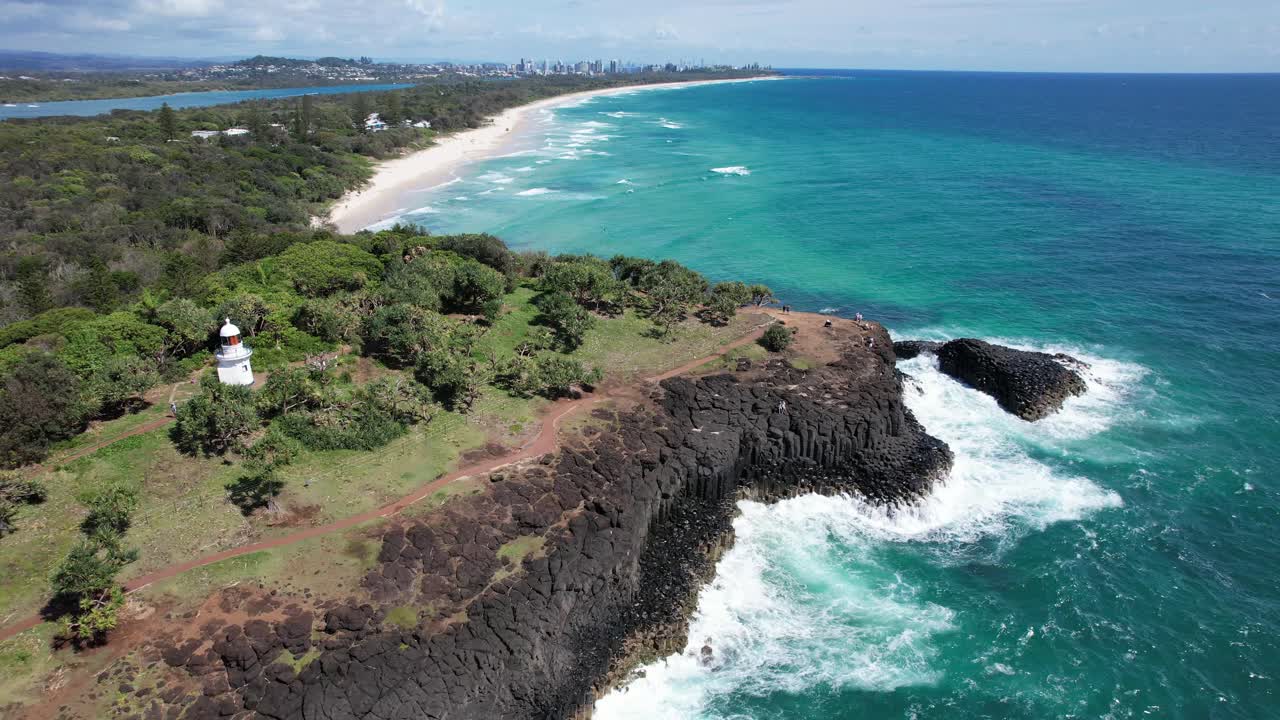 Aerial View of Coastline with Lighthouse and Waves Crashing on Rocks