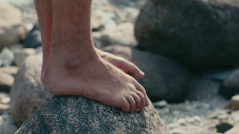 Hombre-De-Pie-Descalzo-En-La-Cima-De-La-Roca-Cerca-De-La-Playa,-Primer-Plano