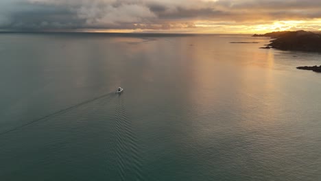a boat sails across the calm ocean water close to the coast of oneroa at sunrise