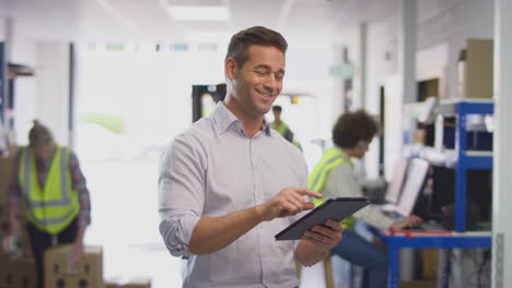 male manager in busy logistics distribution warehouse using digital tablet