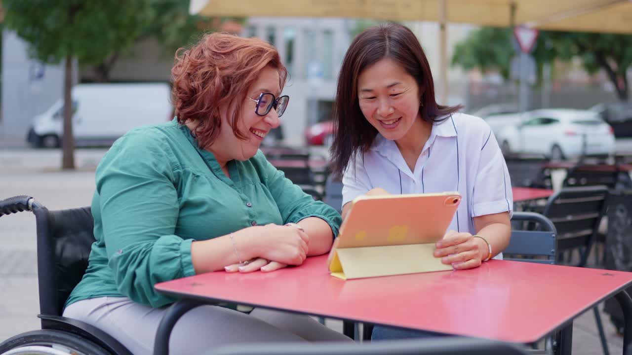 Two women looking at a tablet at a table