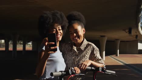 Two-mixed-race-women-taking-picture-under-bridge