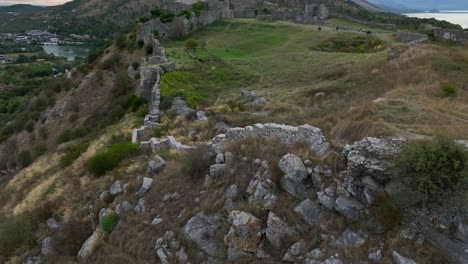 aerial establishing of ancient ruins in scodra, albania, rolling hills and historic landscape with broken walls and footpaths