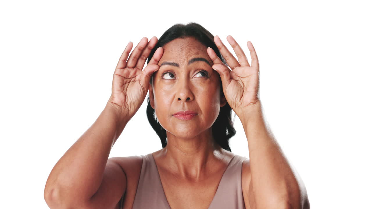 Mature Woman Examining Wrinkles on Her Forehead Against White Background