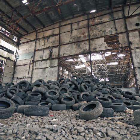 big old empty factory with garbage and a pile of used rubber tyres inside. tires that are no longer suitable for use on vehicles in a damaged plant.