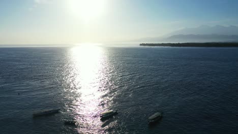 direct sunlight over the tropical ocean with islands in the background, aerial revealing moored fishing bots