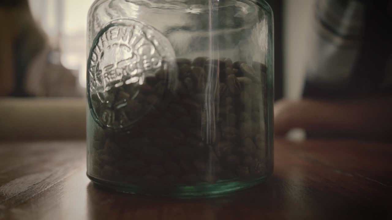 granos de café recién tostados que caen en un recipiente de vidrio, de abajo hacia arriba