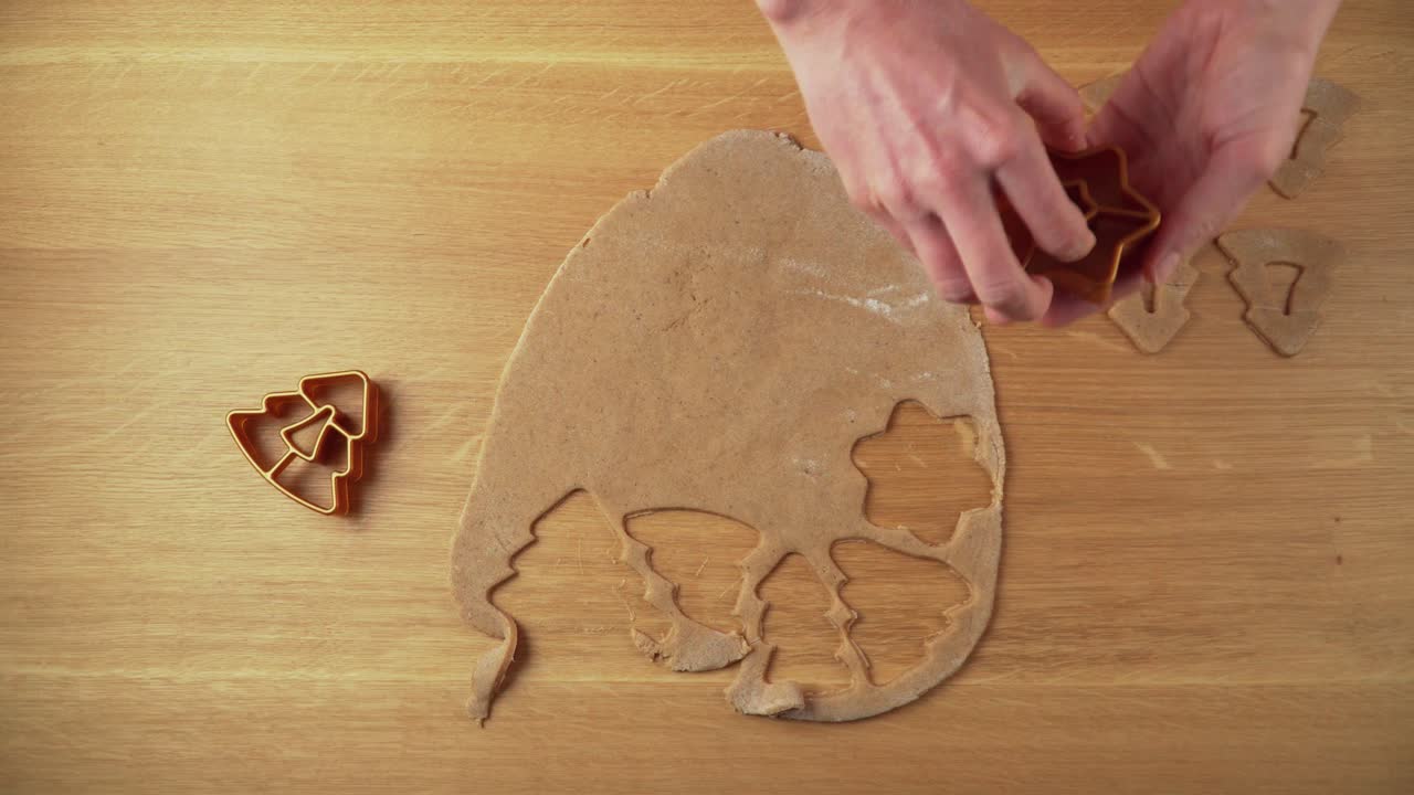 Making christmas shapes from gingerbread dough on a wooden table topdown video