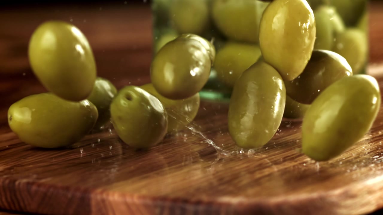 Olive verdi fresche che schizzano su una superficie di legno
