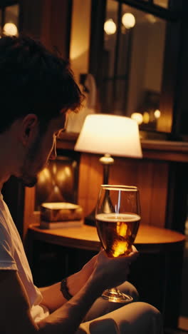 man reading and drinking beer at night