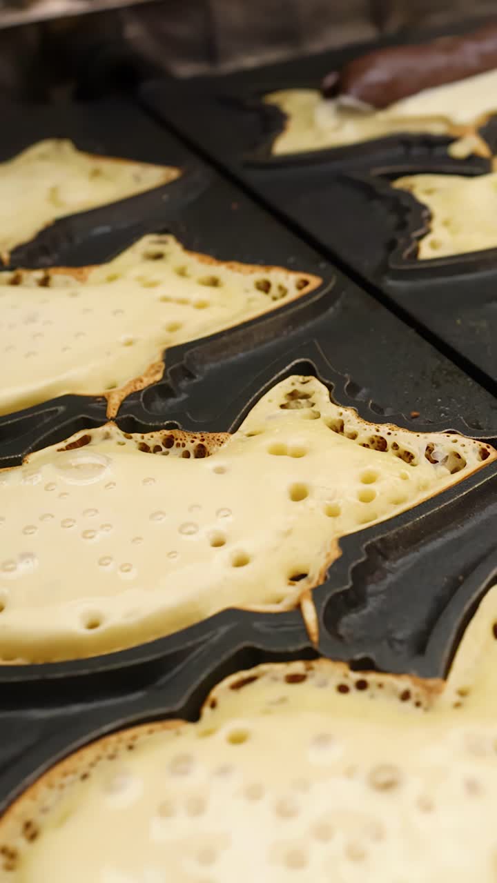 Batter bubbles in fish-shaped molds as traditional Japanese street food cooks on a griddle