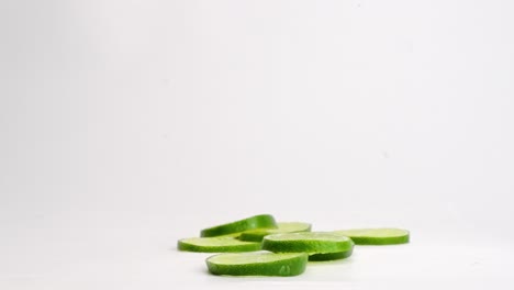 juicy lime slices falling onto white table top, spraying juice while bouncing and landing in a pile in slow motion