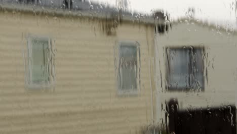 rain on a uk static caravan window, with caravan in background