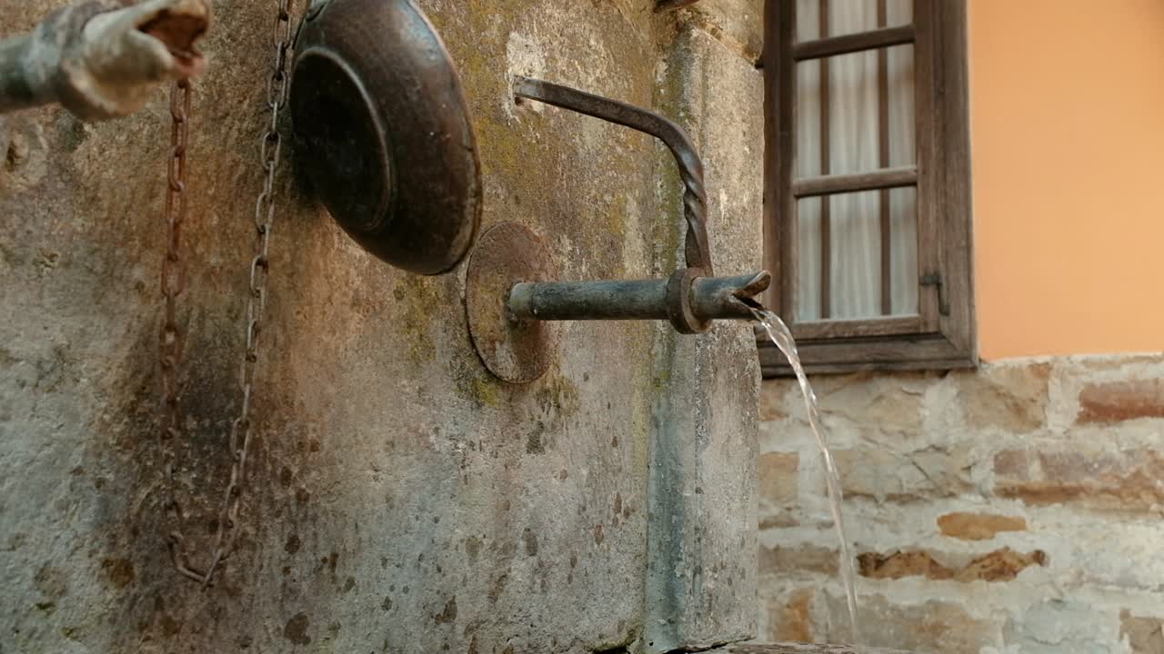 Acqua corrente fredda di sorgente da un'antica fontana di un villaggio.