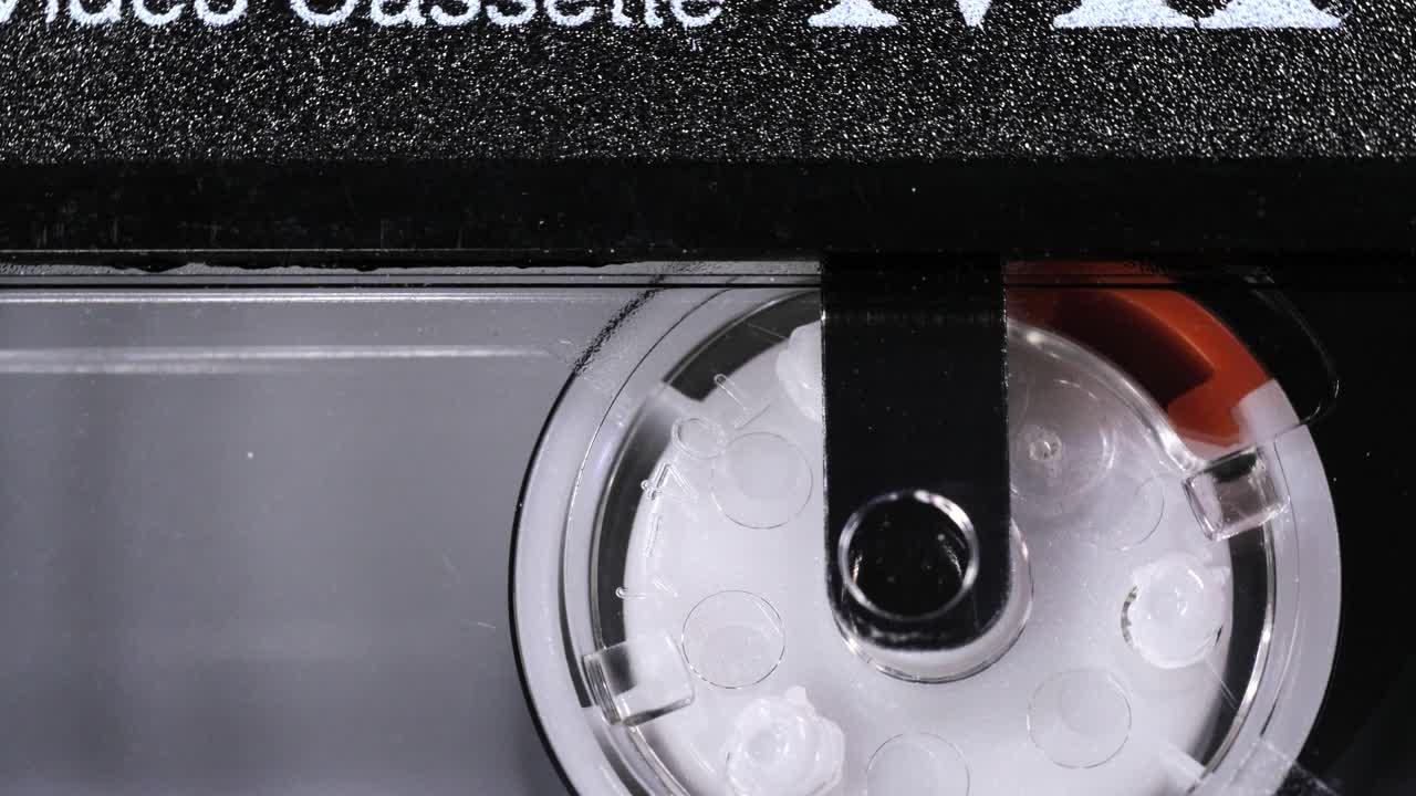 Primo piano in rotazione di una vecchia cassetta per videocamera con dettagli visibili della bobina.