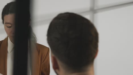 male candidate being interviewed in office for job by female interviewer viewed through window 4