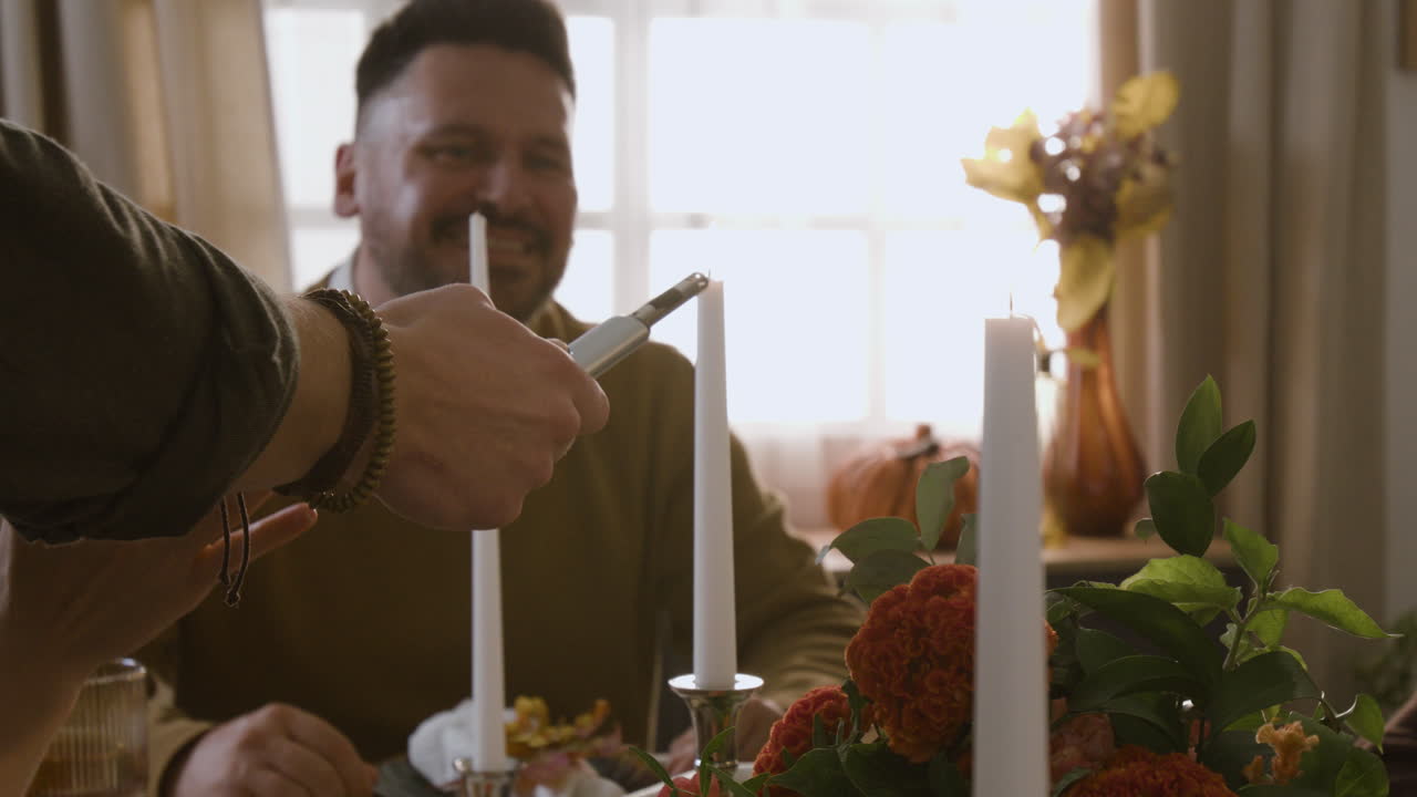 People lighting candles at a dinner table