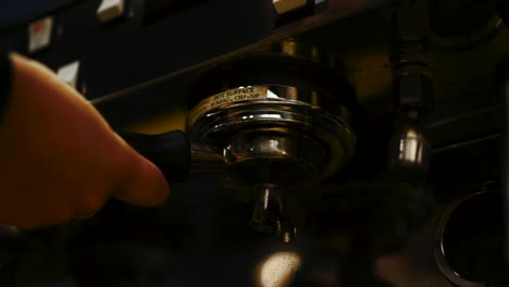 Close-up-tilt-up-shot-of-barista-using-a-portafilter-to-carrie-a-tamped-puck-of-coffee-grounds-and-sealing-with-the-espresso-machine's-gasket---slow-motion