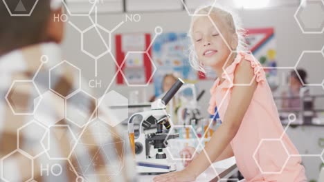 Animation-of-elemental-diagrams-over-smiling-caucasian-schoolgirl-using-microscope-in-science-class